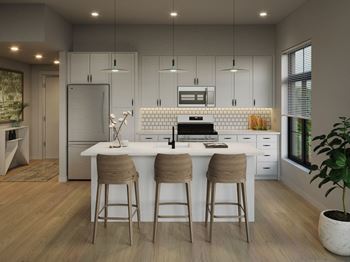 A modern kitchen with a white island and bar stools.at Aviator Lofts, Newport News, VA